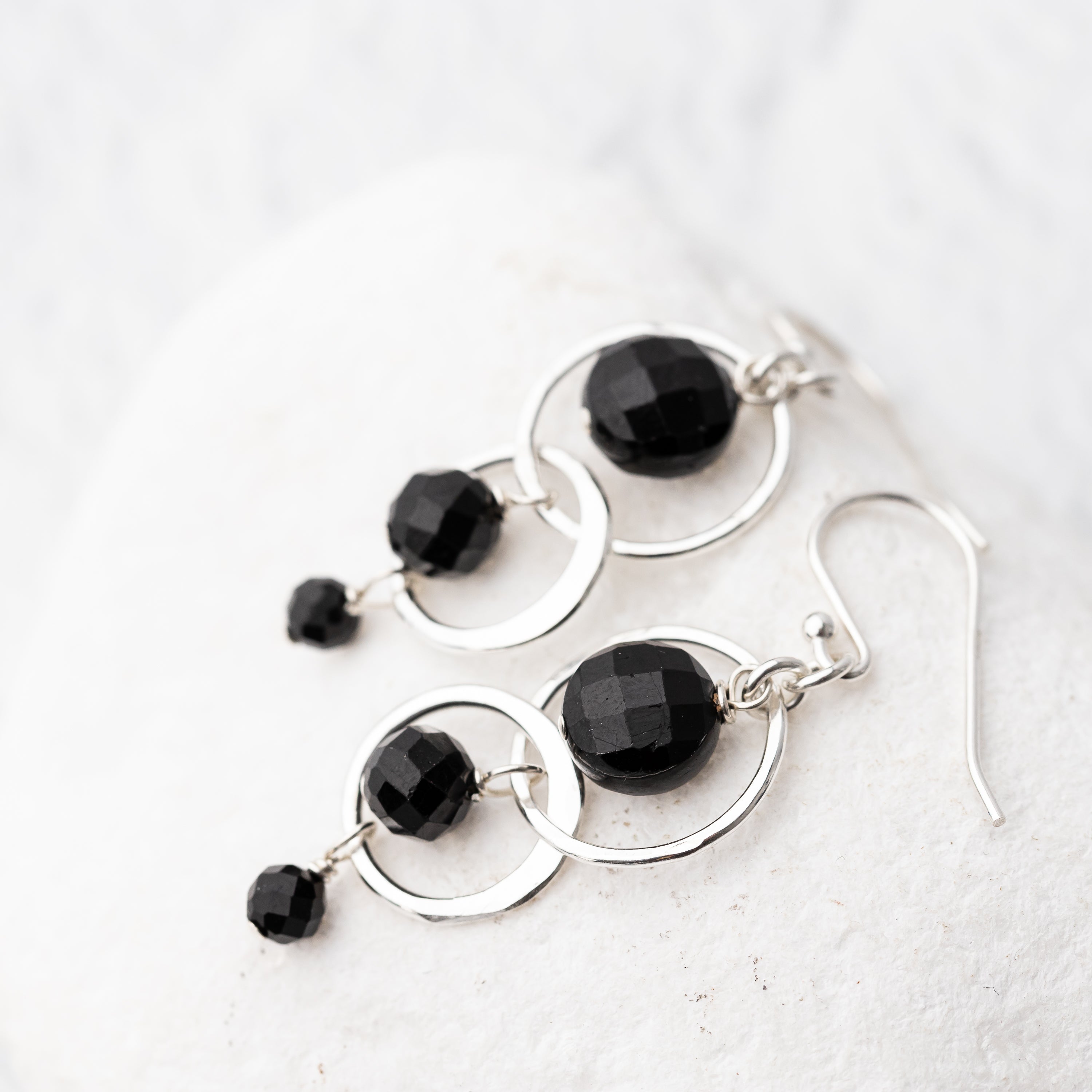 handmade Black tourmaline earrings with sterling silver circular designs on a white background
