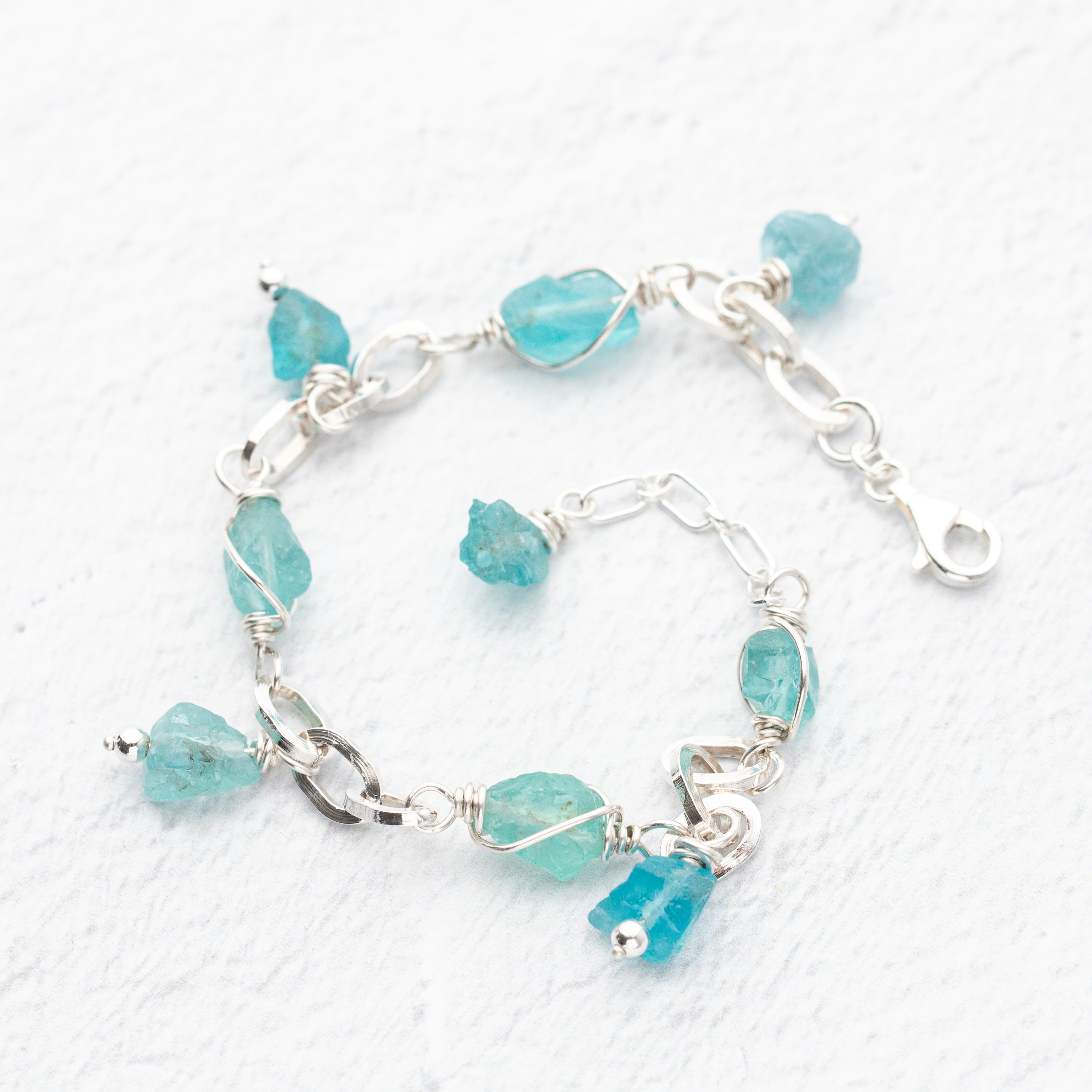 Turquoise blue apatite stone  beaded bracelet with silver chain on a white background