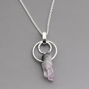 Handmade sterling silver necklace with a circle pendant and purple amethyst crystal on a gray background
