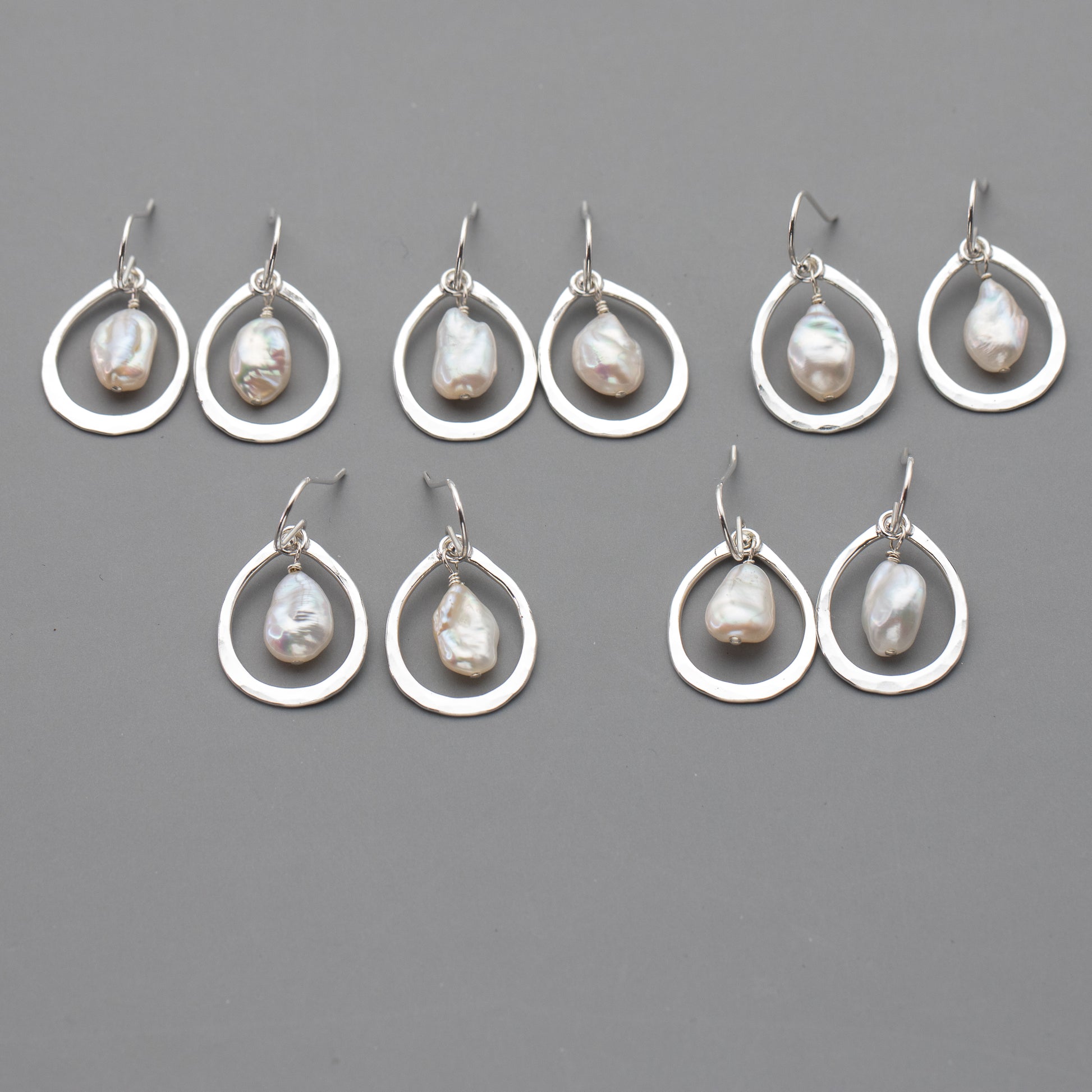 Set of silver earrings with pearl drops on a gray background