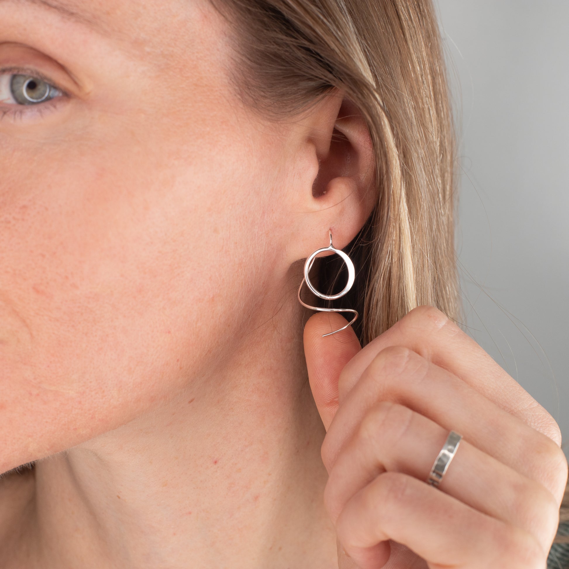 Close-up of a woman wearing a silver hoop earring with a blurred background