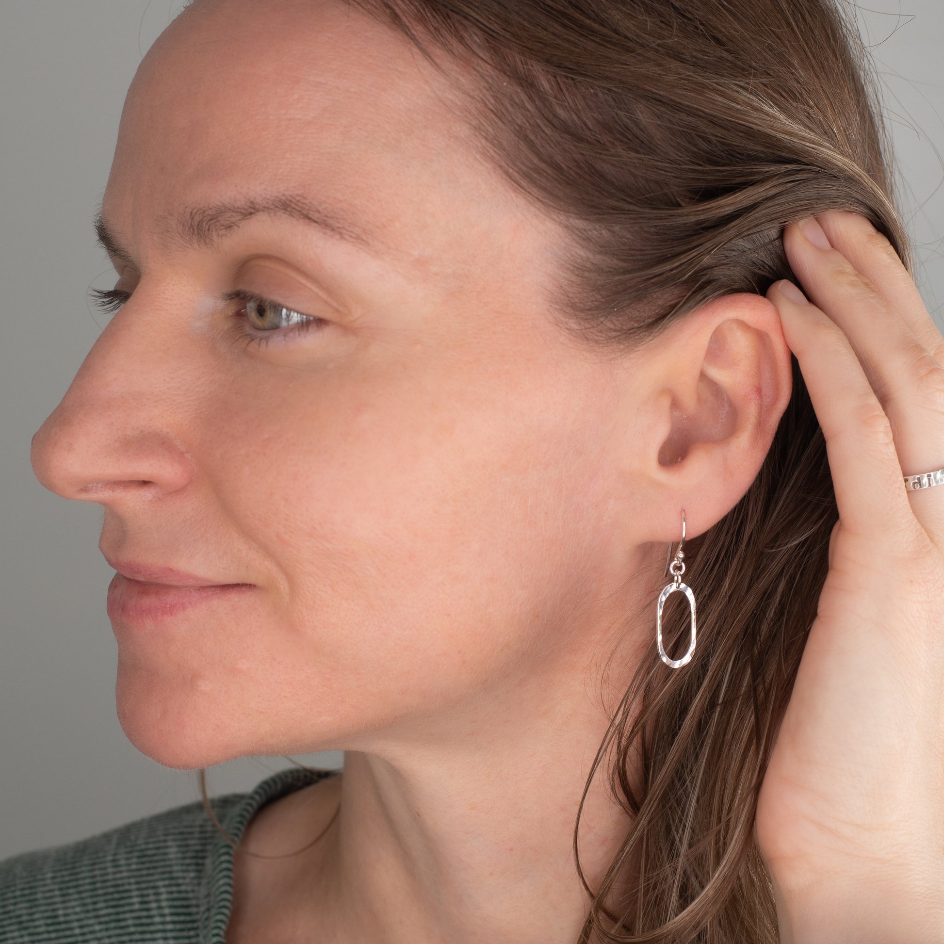 Close-up of a woman wearing a silver earring against a neutral background