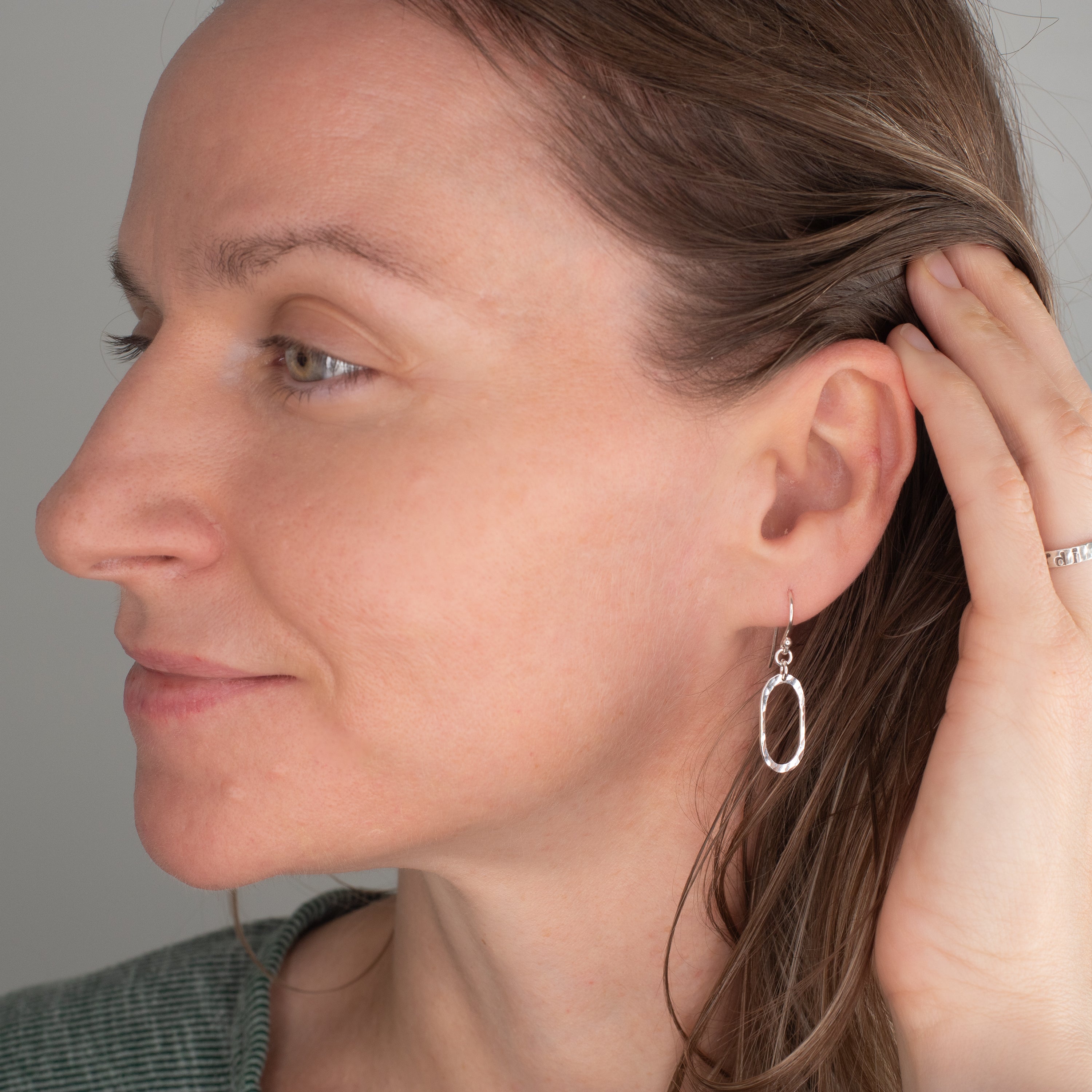 Close-up of a woman wearing a silver earring against a neutral background
