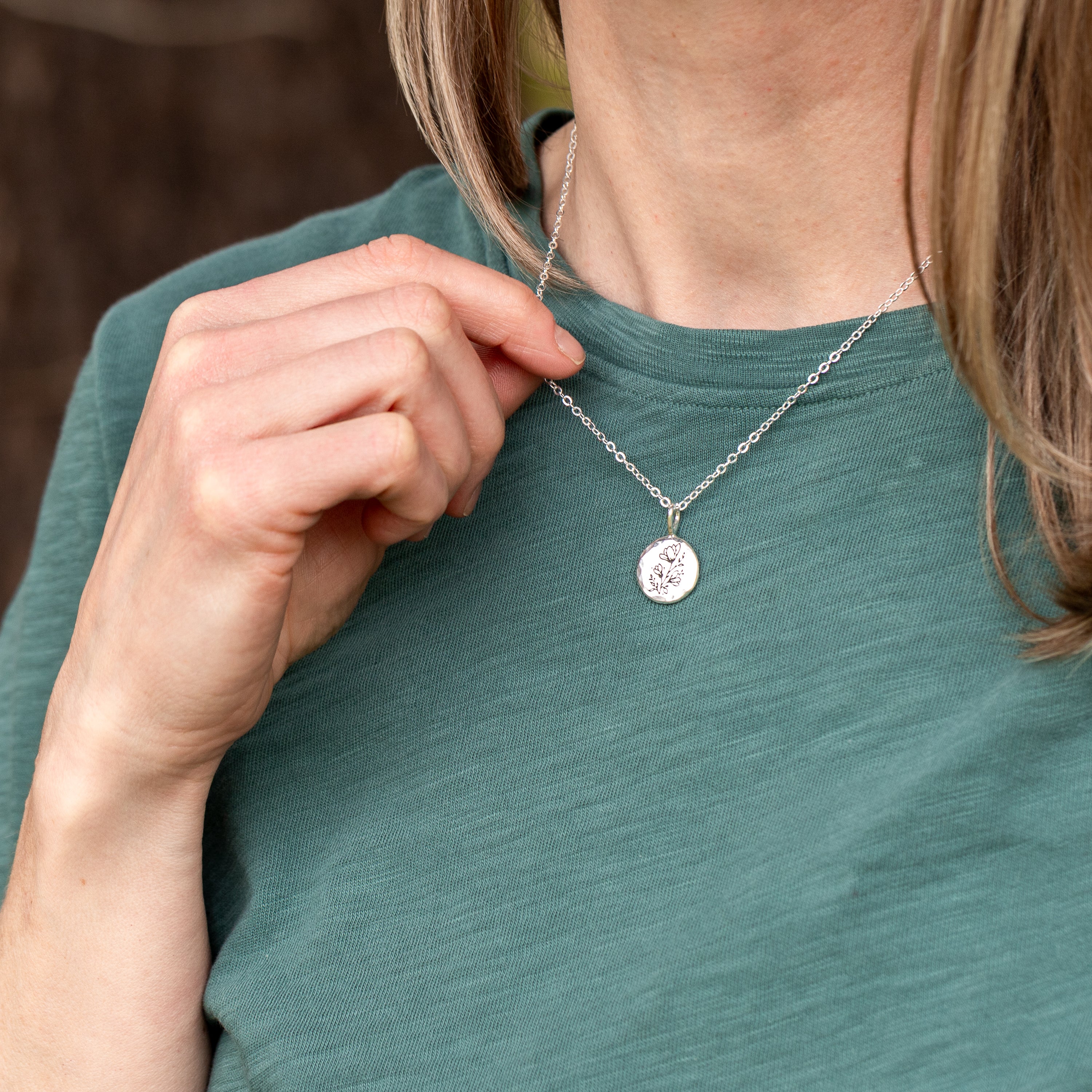 Close-up of bright polished silver pendant with engraved flowers